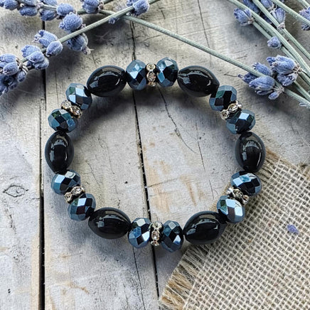 Cherry Pit Crafts black oval beads and faceted blue crystals stretch bracelet with silver accents.