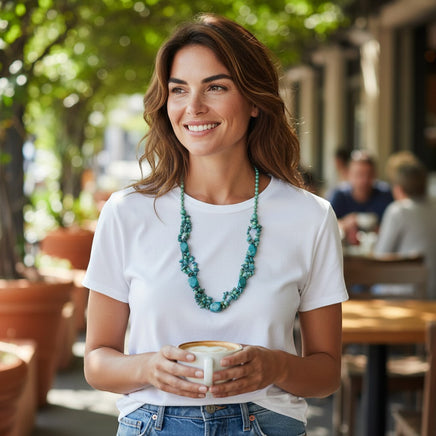 Cherry Pit Crafts handmade turquoise beaded necklace with natural stone variations, worn by a woman holding a coffee cup.