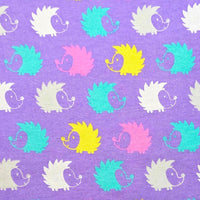 Cherry Pit Crafts microwaveable heating pad fabric with a repeating pattern of hedgehogs in white, yellow, pink, and teal on a purple background.