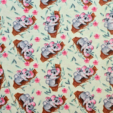 Cherry Pit Crafts light green fabric with a repeating pattern of koalas and pink flowers.