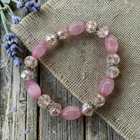 Cherry Pit Crafts pink beaded stretch bracelet with smooth beads and faceted crystals on a flexible band.