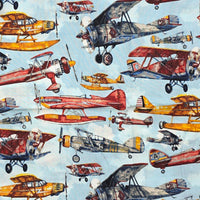 Cherry Pit Crafts vintage airplane print heating pad fabric with biplanes and seaplanes in red, yellow, and blue.