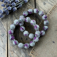 Cherry Pit Crafts elegant white glass bead stretch bracelets with purple ink detailing and rhinestone accents.